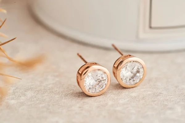 Close up golden stud earrings, with white crystals and diamonds. Beautiful earrings on white background.