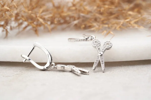 Срібні сережки ізольовані, з білими кристалами у вигляді ножиць. Красиві сережки на білому тлі . — стокове фото