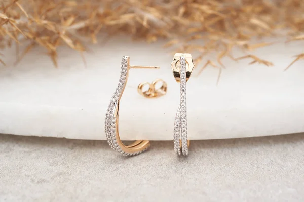 Золоті сережки ізольовані, з білими кристалами та діамантами. Красиві сережки на білому тлі Стокове Фото