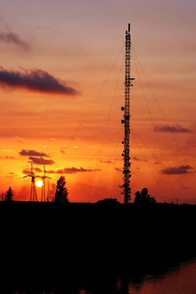 cellular tower at sunset on the river bank