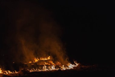 Baharda geceleri bir tarlada yanan otlar.