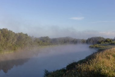 Şafakta nehrin üzerinde sis var.