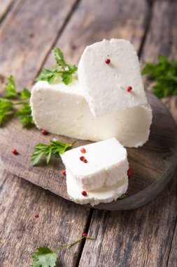 Suluguni peyniri ahşap bir tahtanın üzerinde büyük parçalara ayrılır. Maydanoz yaprakları ve biberle süslenmiş..