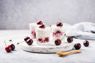 Kiraz çilekli Chia pudingi, doğal yoğurt, gri bir yüzeyde bir bardak. Seçici odaklanma. Sağlıklı tatlı, düzgün beslenme, süper yemek..