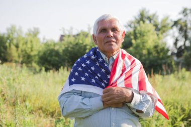 Vatansever kıdemli adam 4 Temmuz 'da elinde ulusal bayrağıyla Amerika' nın bağımsızlığını kutluyor. Anayasa ve Vatandaşlık Günü. Ulusal Büyükanne ve Büyükbaba Günü