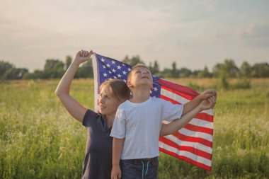 Küçük çocuk yeşil alanda Amerikan bayrağının rüzgarda dalgalanmasına izin veriyor. Vatansever aile 4 Temmuz 'da Amerika' nın bağımsızlığını kutluyor. Anayasa ve Vatanseverlik Günü.