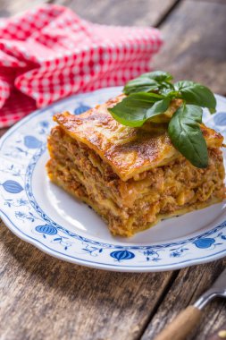 Tahta masadaki tabakta taze fesleğen ve parmesan peynirli et lazanyası. Kapat. İtalyan yemeği..