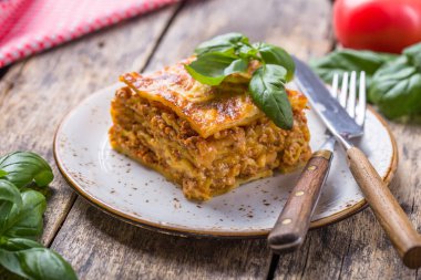 Tahta masadaki tabakta taze fesleğen ve parmesan peynirli et lazanyası. Kapat. İtalyan yemeği..