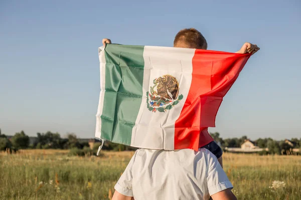 Young boy holding flag of Mexico. \