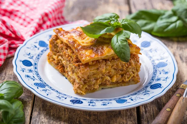 Tahta masadaki tabakta taze fesleğen ve parmesan peynirli et lazanyası. Kapat. İtalyan yemeği..