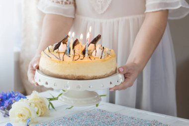 Karamelli elmalı cheesecake ile süslenmiş mumlu bir kadın. Sonbahar tatlısı. Elmalı karamelli cheesecake, tatlı yemek..