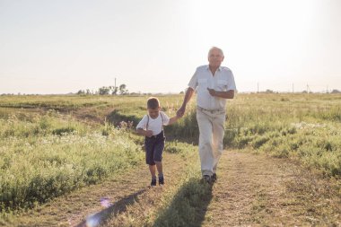 Büyükbabasıyla çayırda oynayan mutlu bir çocuk. Büyükbaba emekli oldu. Emeklilik ebeveyni