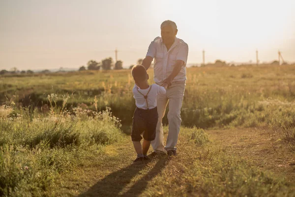 快乐的老人爷爷和可爱的小男孩孙子在田里玩耍 — 图库照片