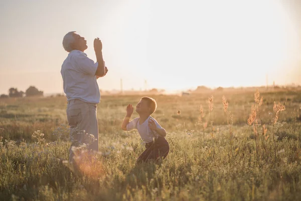 Happy senior man Grandfather with cute little boy grandson playing in field. Happy child with Grandfather playing outdoors