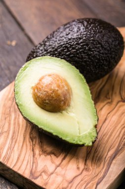 Ahşap arka planda iki Haas avokado meyvesi. Avokadoyu dilimle