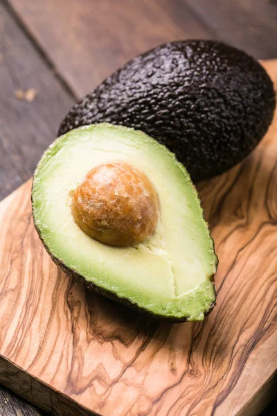 Ahşap arka planda iki Haas avokado meyvesi. Avokadoyu dilimle
