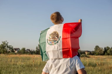 Young boy holding flag of Mexico. 