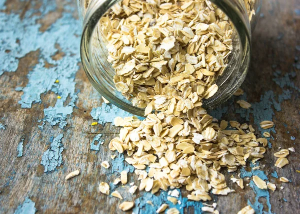 Dry oat flakes, oatmeal on a wooden background. Healthy vegan, vegetarian food. Clean eating, dieting, weight loss concept