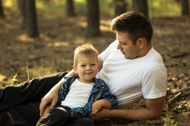 Küçük oğluyla dışarıda eğlenen mutlu genç bir baba. Aile hayatında mutluluk ve uyum..