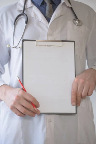 Doctor with stethoscope on the neck holding pencil and copy space list