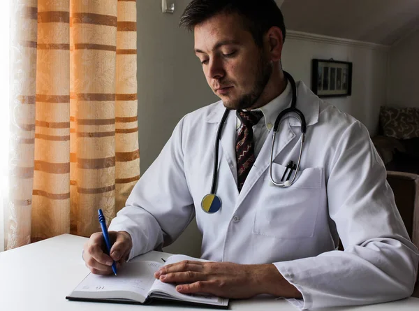 Medical portrait. Male doctor writing in notebook. Young caucasian male medical professional.