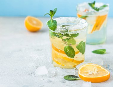 Limonlu limonata suyu. Sağlıklı dilimlenmiş ve detoks suyu. Yazın mavi arka planda.