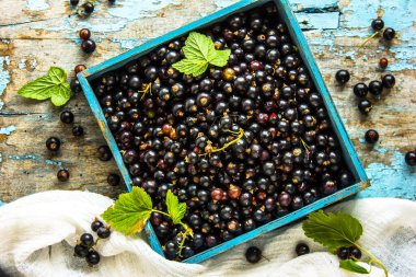 Taze siyah frenk üzümü ahşap bir kutuda mavi eski püskü arka planda.