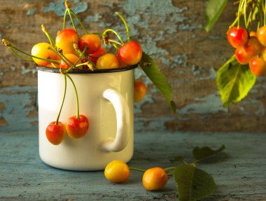 Taze sarı bir kiraz (chereshnya) mavi arka planda beyaz bir fincanda.