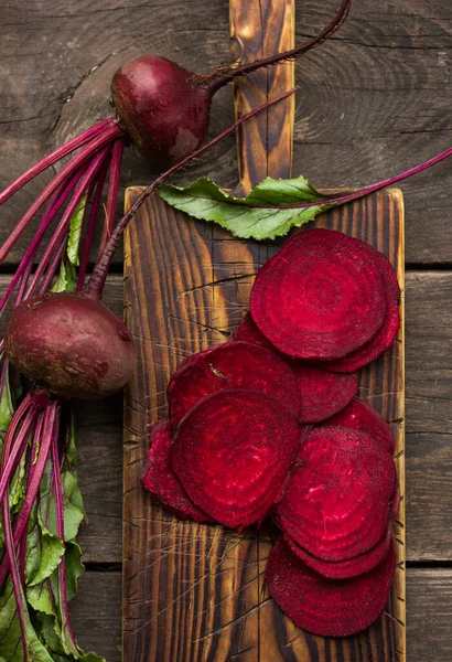 Fresh Whole and cut beetroots with leaves on wooden table.