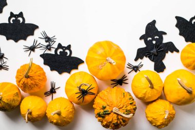 Pastel beyaz arka planda cadılar bayramı dekorasyonu çerçevesi. Turuncu balkabakları, ürkütücü örümcekler, yarasalar, böcekler yatıyordu. Kopyalama alanı olan üst görünüm. Tatil tebrik kartı modeli..