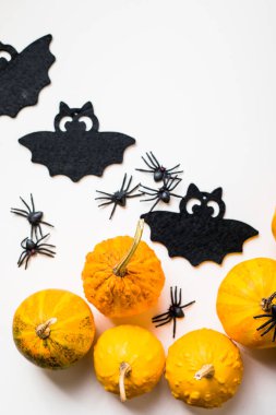 Pastel beyaz arka planda cadılar bayramı dekorasyonu çerçevesi. Turuncu balkabakları, ürkütücü örümcekler, yarasalar, böcekler yatıyordu. Kopyalama alanı olan üst görünüm. Tatil tebrik kartı modeli..