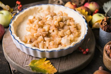 Çiğ geleneksel elmalı turta, malzemeler ve çatal bıçaklarla pişirme. Taze meyvelerle çevrili ev yapımı kek.