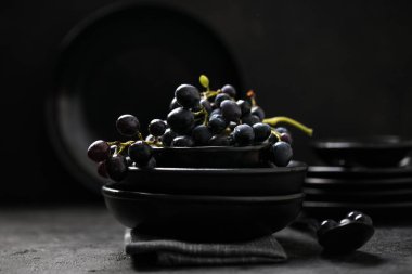 Siyah arka planda, üzümlü, boş, yuvarlak siyah bir plaka. Boşluğu kopyala.