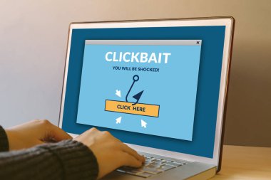 Clickbait konsept dizüstü bilgisayar ekranında ahşap masa üzerinde. Tipik bir klavye üzerinde eller. Tüm ekran içerik bana tarafından tasarlanmıştır. 