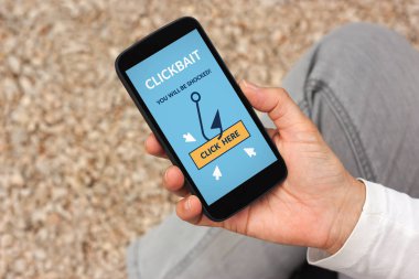 Clickbait konsepti ile akıllı telefon ekranında tutan el. Tüm ekran içerik bana tarafından tasarlanmıştır