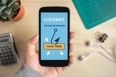 Clickbait konsepti ile akıllı telefon ekranında tutan el. Tüm ekran içerik bana tarafından tasarlanmıştır. Düz yatıyordu