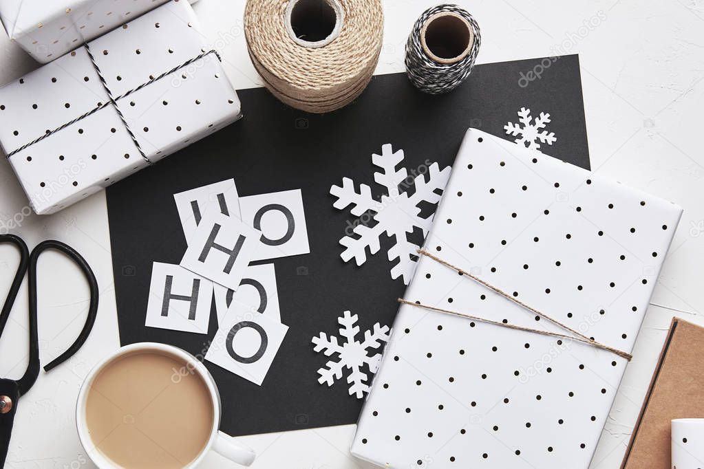 Flat lay Christmas composition with gift boxes and snowflakes in black and white colors. Gift wrapping. Top view
