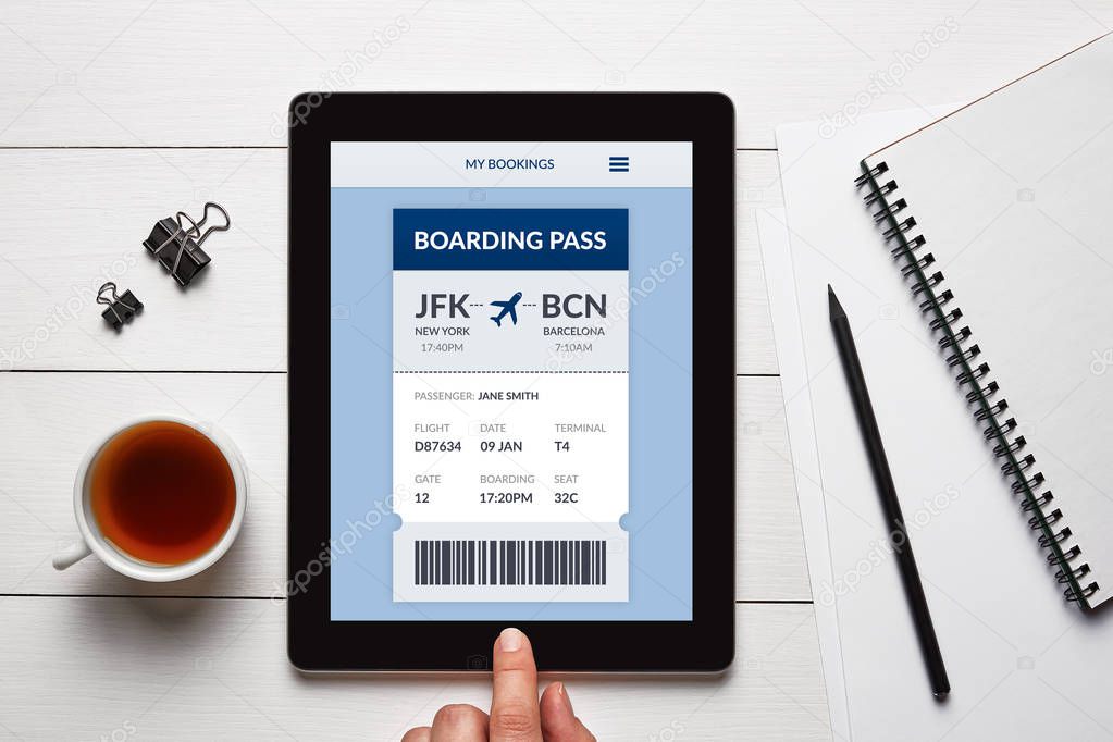 Boarding pass concept on tablet screen with office objects on white wooden table. All screen content is designed by me. Flat lay