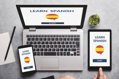 İspanyol konsept dizüstü bilgisayar, tablet ve akıllı telefon ekranında gri masa üzerinde öğrenin. Tüm ekran içerik bana tarafından tasarlanmıştır. Düz yatıyordu