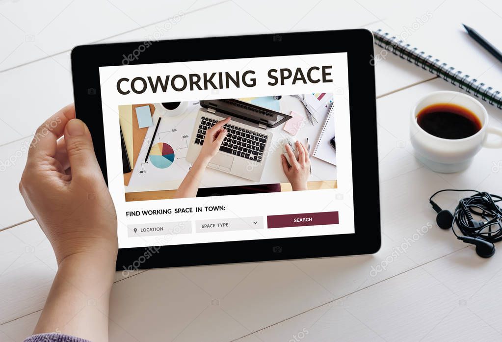 Hand holding tablet with coworking space concept on screen