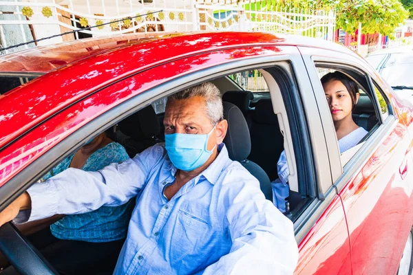 Older man in a medical mask driving a car in the city, New life in a pandemic
