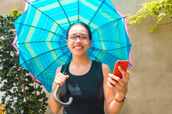 young woman with an umbrella looking at the camera and feeling very excited