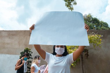 Dışarıda yazı olmayan bir pankart tutan siyah bir protestocu, arkasında boş tabelalar tutan başka insanlar da var.