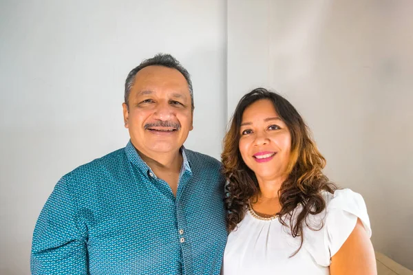 Sabah oturma odasında gülümseyen yetişkin bir çiftin portresi.