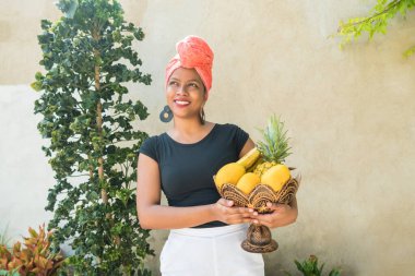 Elinde meyve sepeti tutan Afro-Amerikalı bir çiftçi. Elinde meyve dolu bir sepetle ayakta duran saksı..