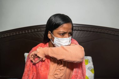 Yüzü maskeli ve grip olmuş hasta bir genç kadın.