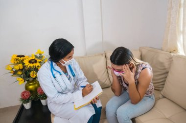 Yüz maskeli bir kadın, doktorla görüşüyor. Tavsiye
