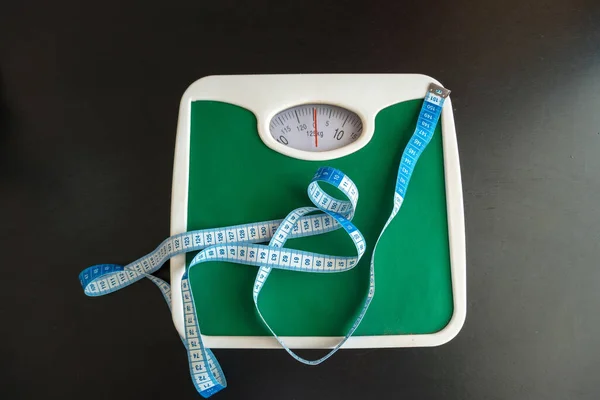 Weight and measuring tape on a black wooden table