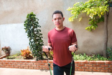 Adam direnç bantları kullanarak pazı egzersizi yapıyor.