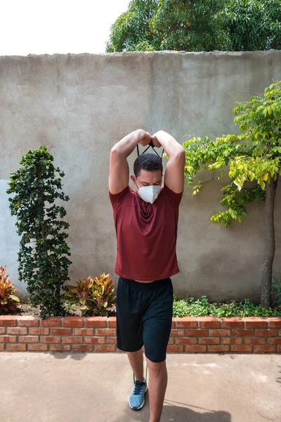 The man with face mask working out with the stretching band. Muscular athlete working out with a rubber band. Man working out with a rubber band. Fit, fitness, exercise, training and healthy lifestyle